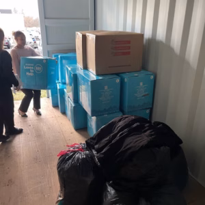 Stacked donation boxes and bagged winter coats stored inside an A-Verdi storage container