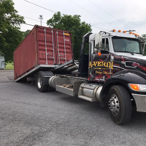 A-Verdi delivery truck unloading a red storage container for rent-to-own customer.