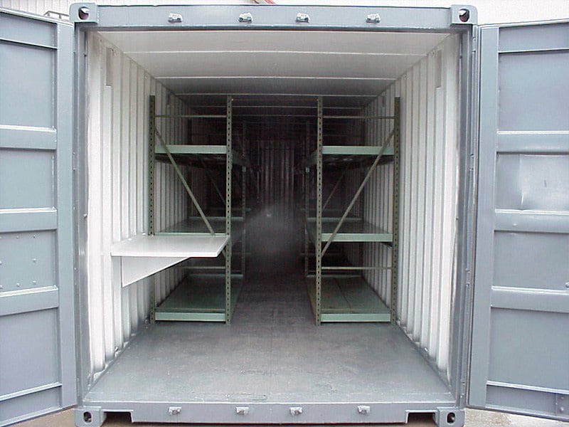 Interior view of a storage container with metal shelving units lining both sides and a fold-down work surface.