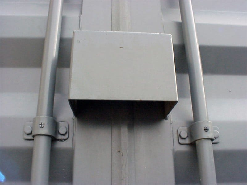 Close-up of a gray steel lockbox welded to a storage container door for added security.