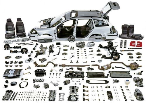 A car completely disassembled into individual parts laid out in organized rows