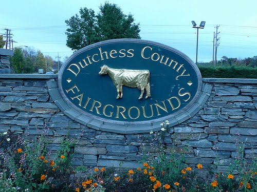 Stone entrance sign for Dutchess County Fairgrounds with a golden cow emblem.