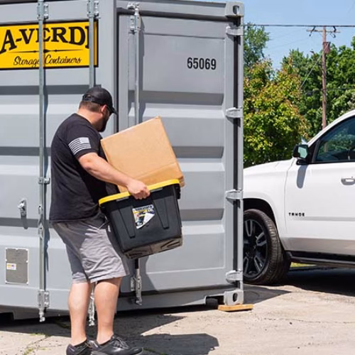 Temporary On-Site Storage for Projects Big and Small Homeowner loading boxes into an A-Verdi residential storage container during a home repair or DIY project.